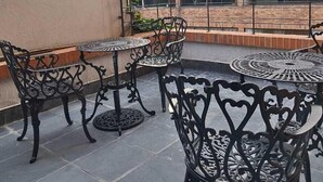 Una terraza en la azotea con asientos exteriores y vistas de edificios circundantes.