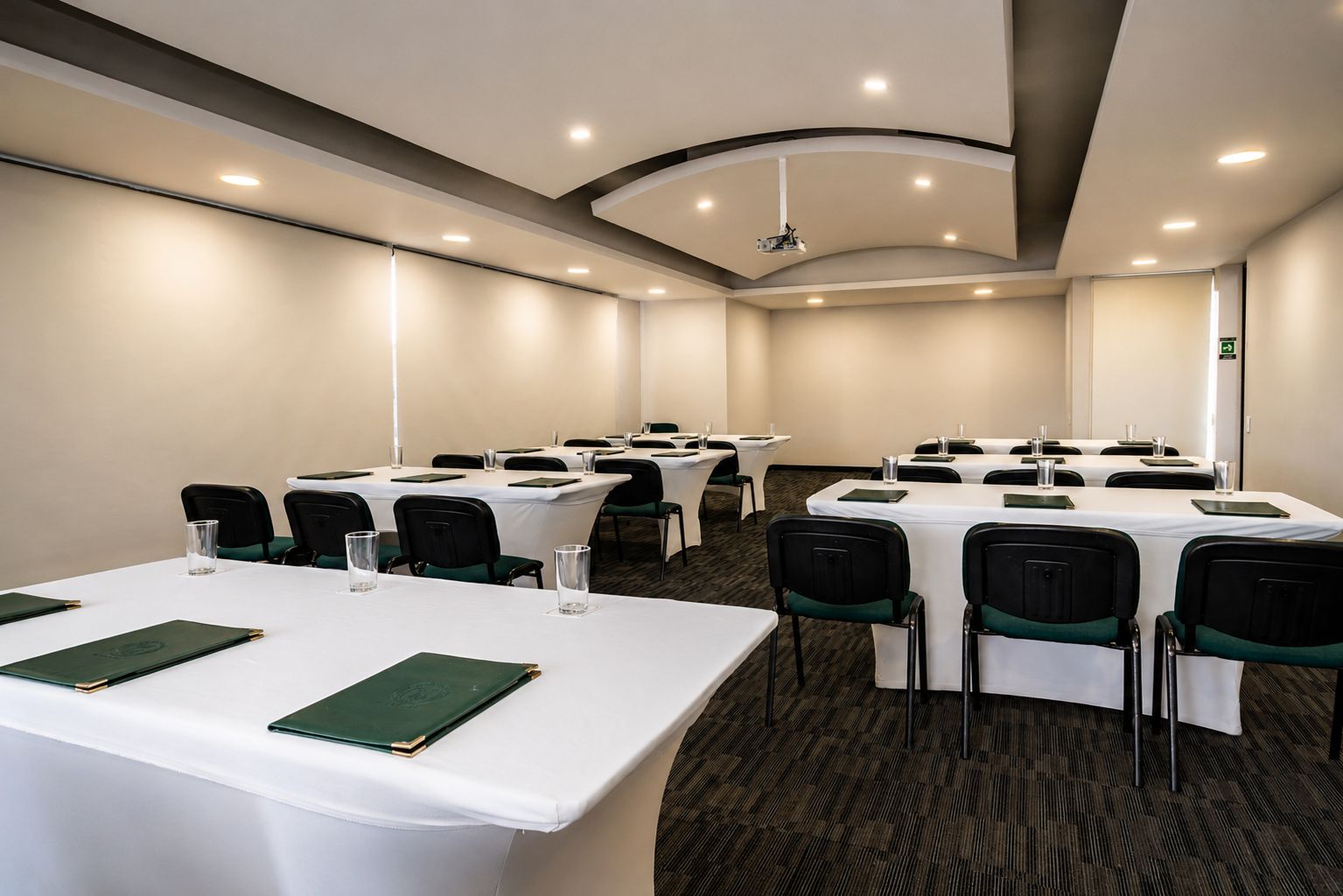 A conference room with multiple tables, chairs, and a carpeted floor.