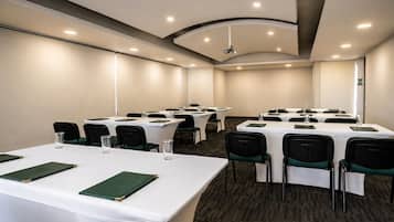 A conference room with multiple tables, chairs, and a carpeted floor.