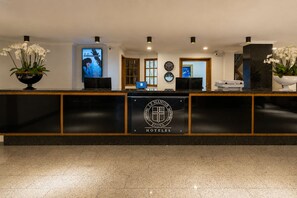 Mostrador de recepción de hotel con un logotipo, una pantalla digital y un reloj.