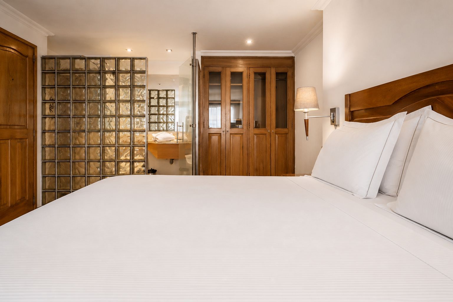 Camera d'albergo con un letto grande, un armadio in legno e un vano vetrato con vista.