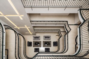 Een modern interieur met een gebogen trap, ingebouwde verlichting en een centraal zithoek met open haard.