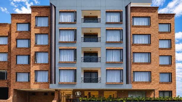 Een hotel met meerdere verdiepingen, een bakstenen gevel, grote ramen en een centrale ingang met een trap.