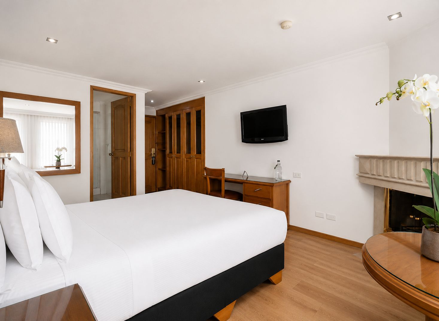 Una habitación de hotel con cama, escritorio, televisor y chimenea.