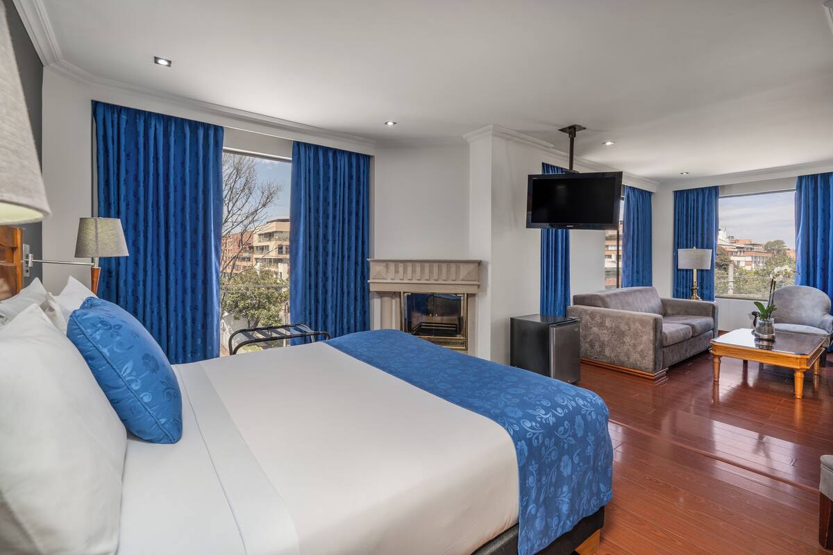 Una habitación de hotel con una cama grande, un sofá, un televisor y una chimenea.
