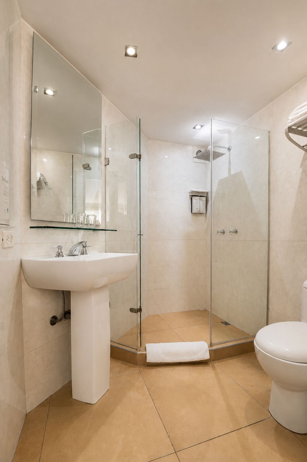 A modern bathroom with a glass-enclosed shower, a white sink, and a toilet.