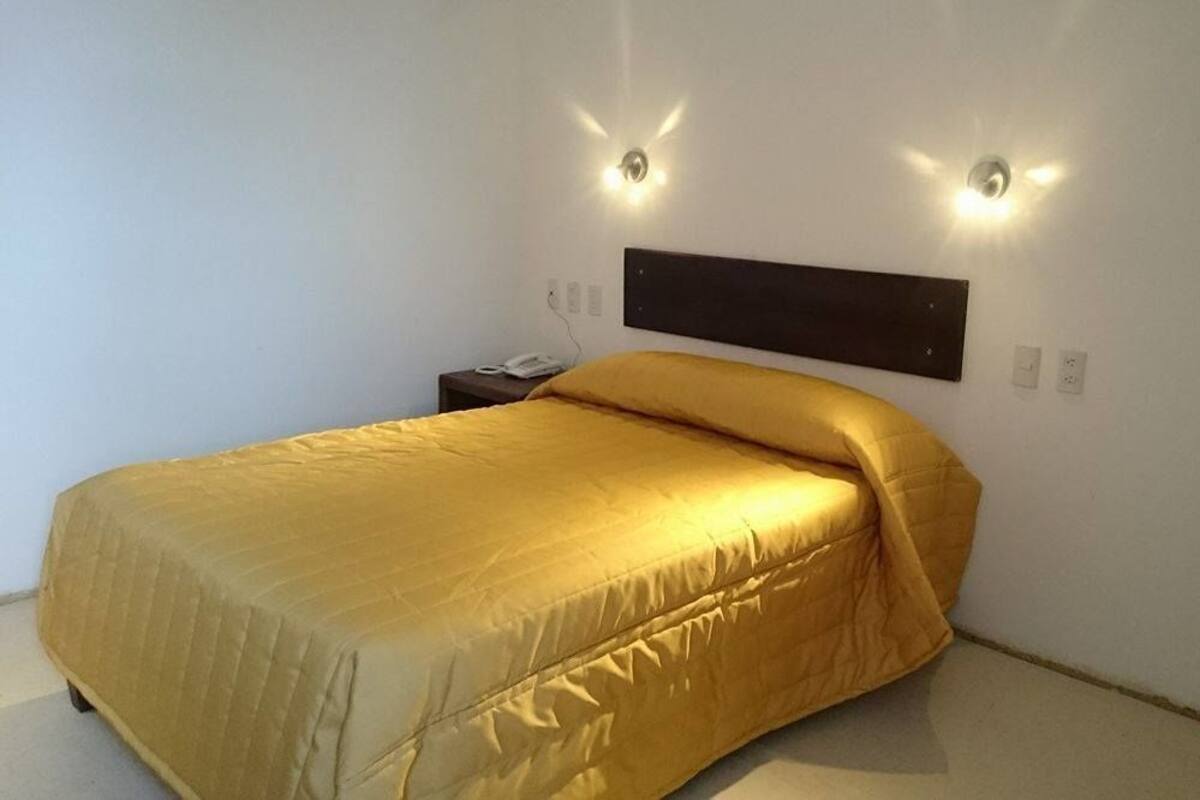 A bedroom with a bed, a nightstand, and two wall-mounted lights.