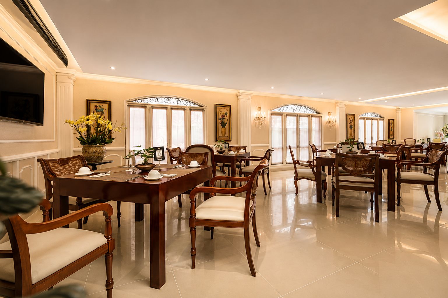 Un comedor amplio con varias mesas y sillas, ventanas grandes y una decoración elegante.