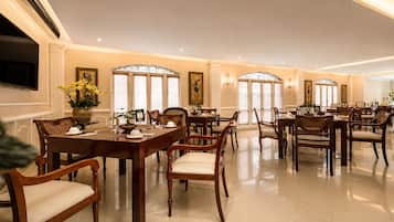 Un vaste espace dédié à la salle à manger, avec de nombreuses tables et chaises, de grandes fenêtres et un décor élégant.