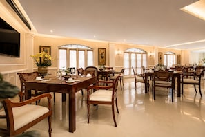 Un comedor amplio con varias mesas y sillas, ventanas grandes y una decoración elegante.