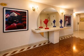 A hallway with a white console table, framed artwork, and a fire extinguisher.
