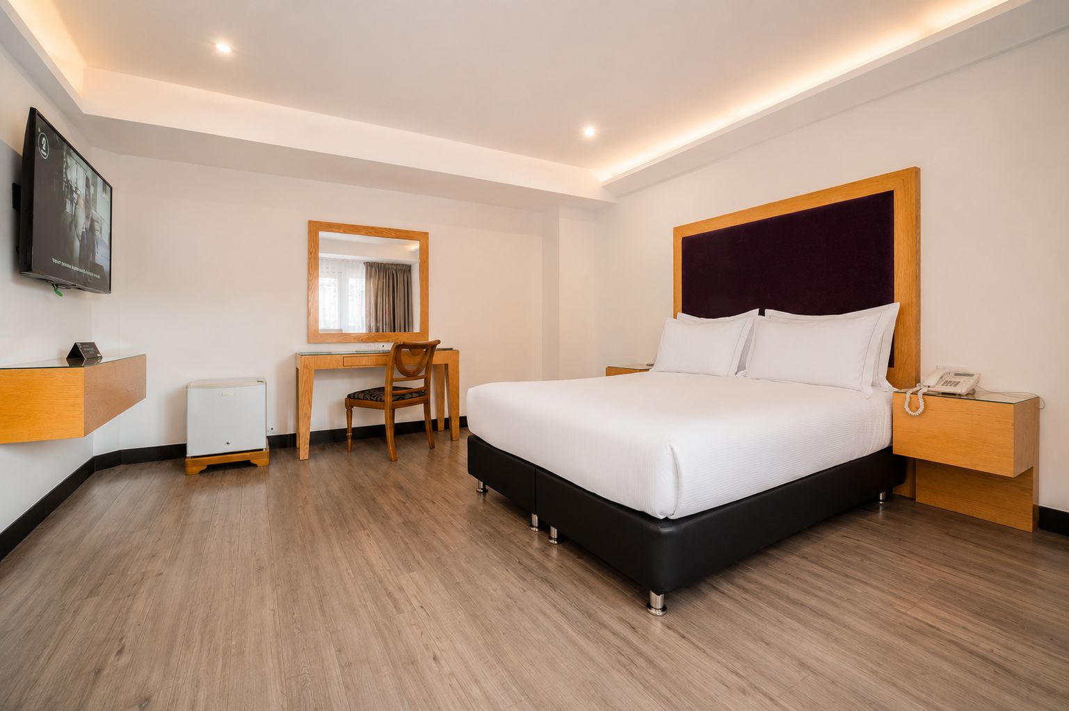 Una habitación de hotel con cama, escritorio, silla y televisor.