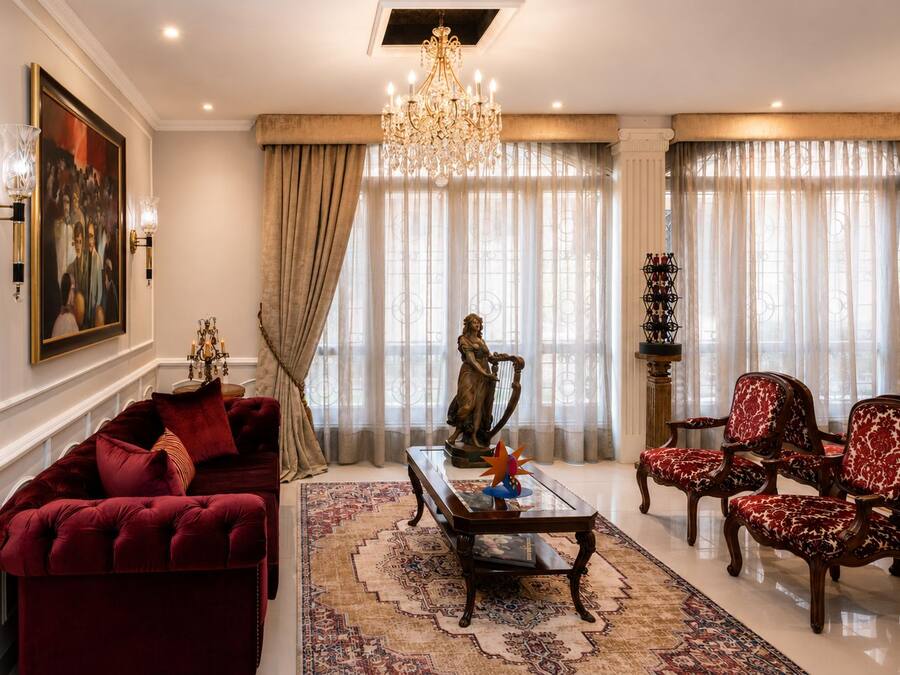 Uma sala de estar ampla com um sofá vermelho, uma mesa de centro e uma estátua.
