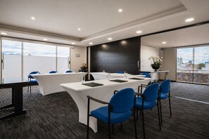 A conference room with a long table, blue chairs, and large windows offering a view. - Hotel Le Manoir Bogota (Bogotá)