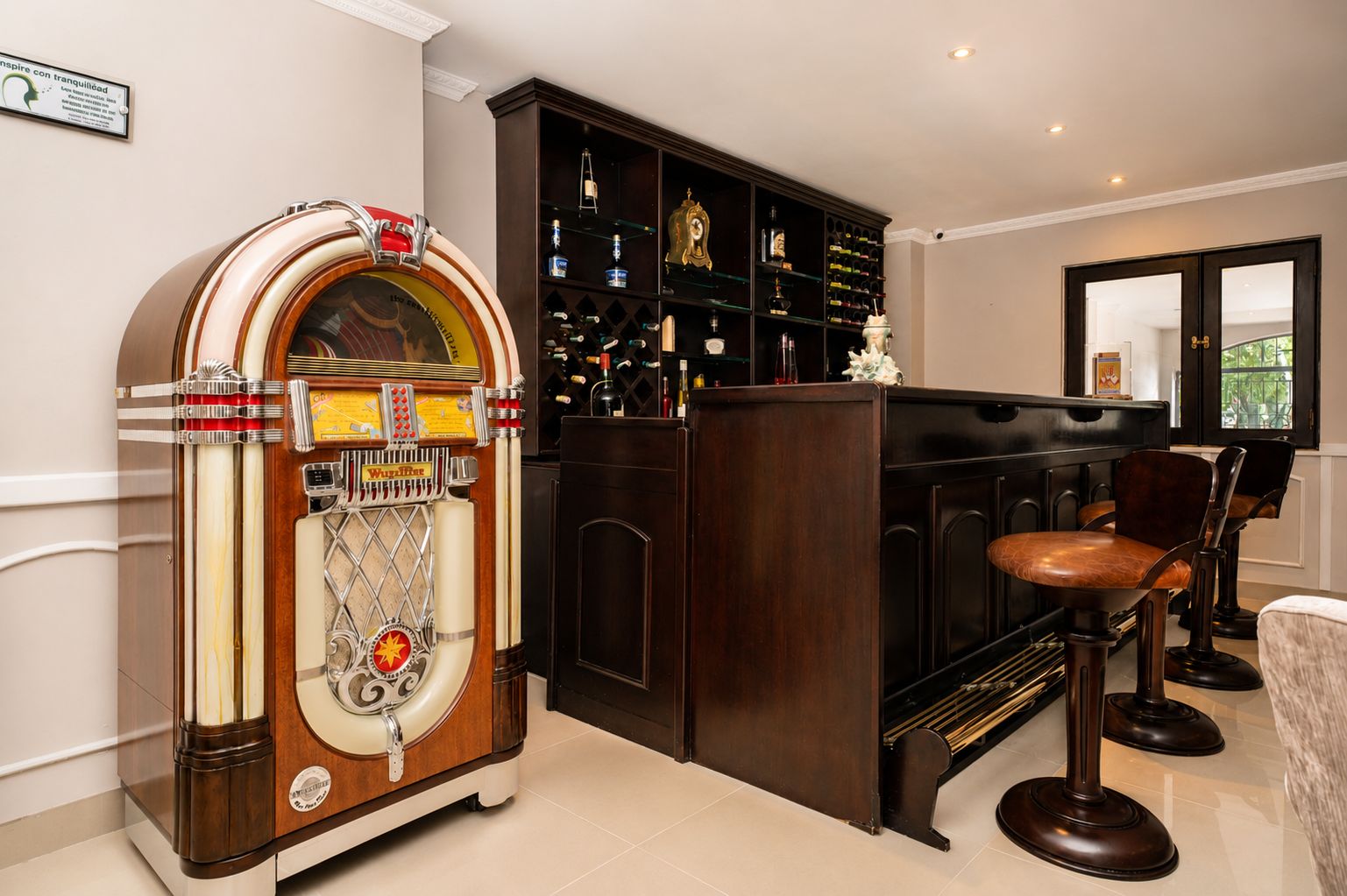 Un jukebox antiguo, una zona de bar con taburetes y una estantería para vinos.