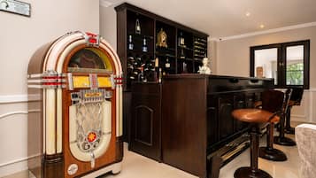 Un jukebox antiguo, una zona de bar con taburetes y una estantería para vinos.