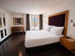 Habitación de hotel con una cama grande, un escritorio, una silla y vistas al exterior.