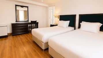 Une chambre d’hôtel avec deux lits, un bureau, une chaise, une commode et un miroir.