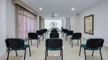 A conference room with rows of chairs, a projector screen, and a framed picture on the wall.
