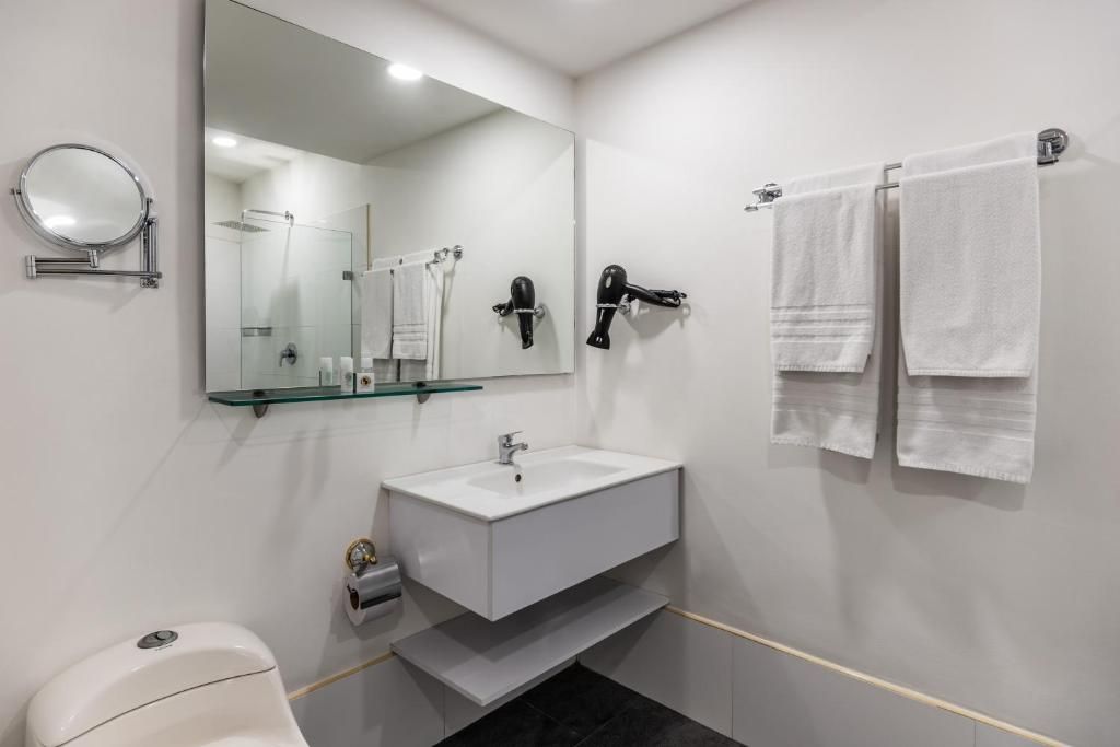 Ein modernes Badezimmer mit einem weißen Waschbecken, einem Spiegel, einem Handtuchhalter und einer Duschkabine.