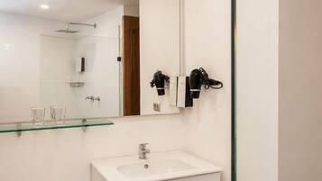 A modern bathroom with a glass shower enclosure, a white sink, and a toilet.
