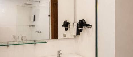 Un baño moderno con cabina de ducha de vidrio, un lavamanos blanco y un inodoro.