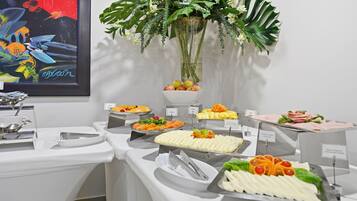 A buffet setup with various food items and a decorative plant.