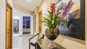 A reception area with a dark wooden reception desk, a potted plant, and a colorful abstract painting on the wall. - Hotel Egina Medellín (Medellín)