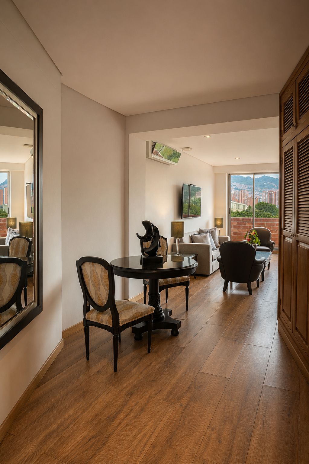 A modern living room with a dining area, a flat-screen TV mounted on the wall, and a view of the cityscape through large windows.