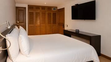 Une chambre à coucher comprenant un lit, une armoire en bois, un téléviseur à écran plat et une table de chevet.