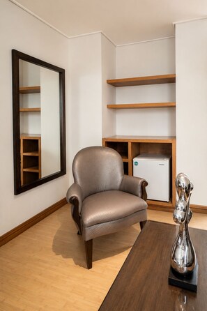A modern room with a leather armchair, a wooden table, a decorative metal sculpture, and built-in wooden shelving. - Hotel Egina Medellín (Medellín)