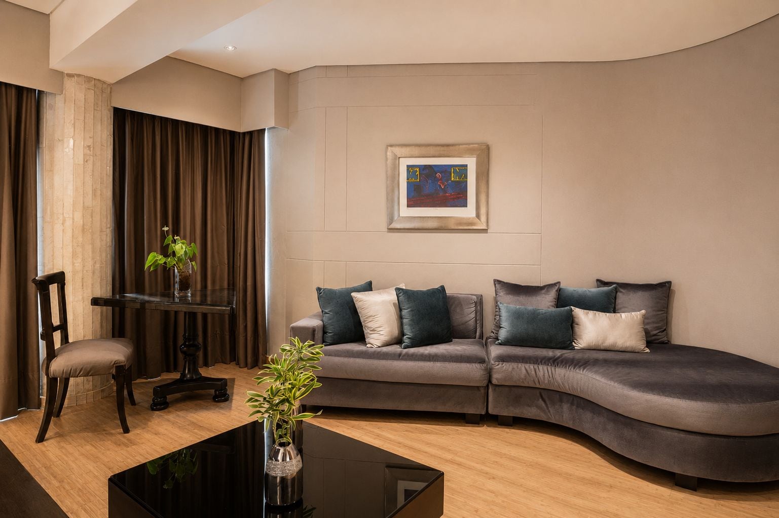 Ein modernes Wohnzimmer mit einer gebogenen Couch, einem Glastisch und einem gerahmten Kunstwerk an der Wand.