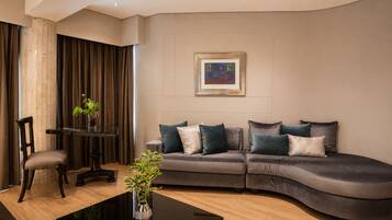 A modern living room with a curved sofa, a glass coffee table, and a framed artwork on the wall.