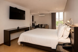 A hotel room with a bed, bedside table, lamp, TV, and a desk. - Hotel Egina Medellín (Medellín)