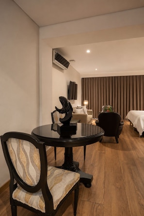 Een hotelkamer met een ronde eettafel, een bank, een bed en een televisie.