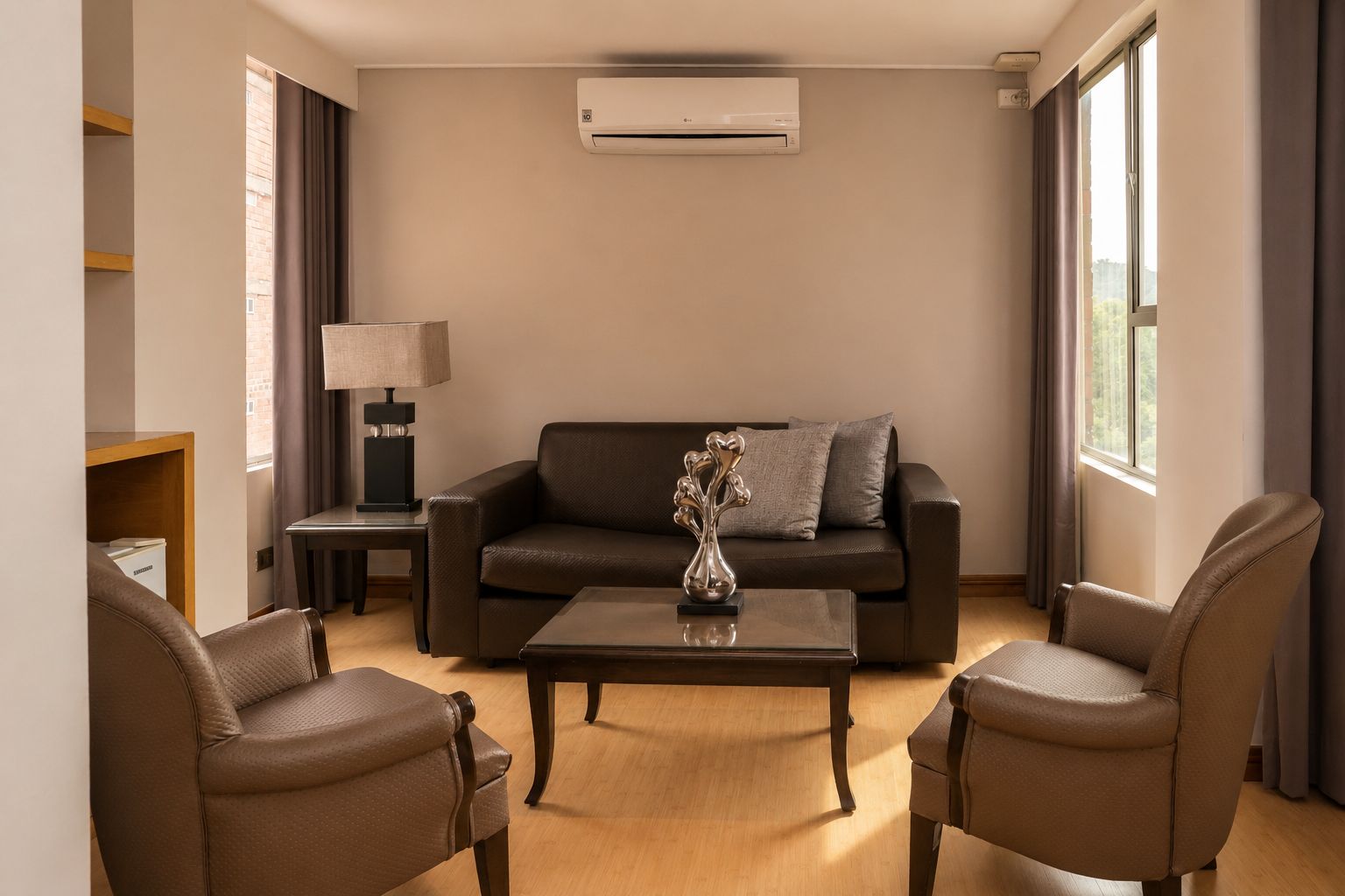 A modern living room with a sofa, two armchairs, a coffee table, a lamp, and an air conditioning unit.