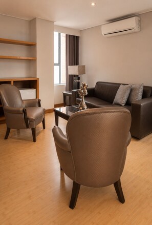 A modern living room with a brown leather sofa, two leather armchairs, a coffee table, and a lamp. - Hotel Egina Medellín (Medellín)