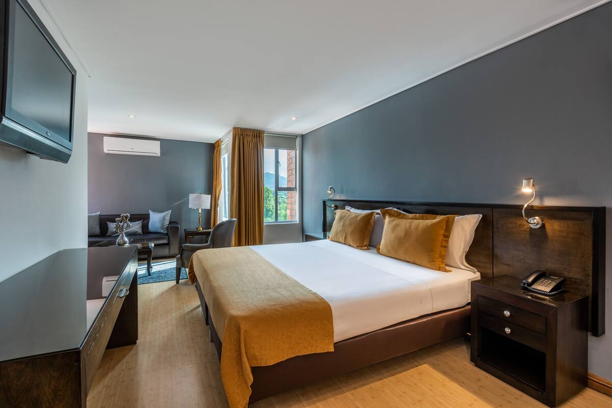 Una habitación de hotel moderna con una cama grande, una mesita de noche y un televisor de pantalla plana en la pared.