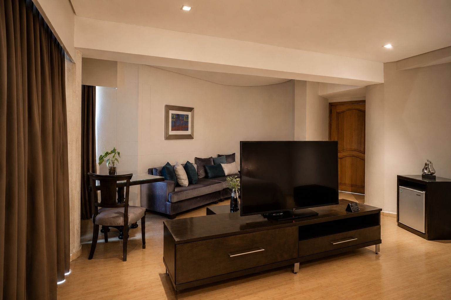 A modern living room with a flat-screen TV, a sofa, a coffee table, and a small cabinet.