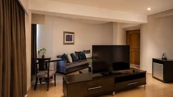 A modern living room with a flat-screen TV, a sofa, a coffee table, and a small cabinet.