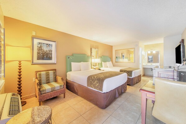A hotel room with a bed, two chairs, a desk, a mirror, and a picture on the wall. - Seasons Florida Resort (Kissimmee)
