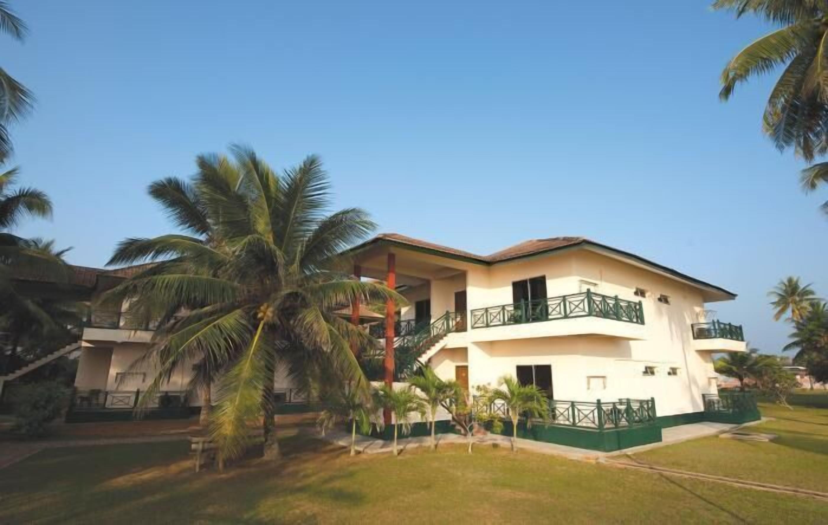 A multi-story hotel with balconies and a well-maintained lawn.