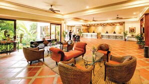 A spacious lobby with wicker furniture, a reception desk, and ceiling fans. - The Qamar Paka (Dungun)
