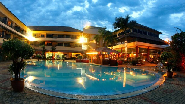 A hotel pool area with a sunken hot tub, palm trees, and a covered seating area. - The Qamar Paka (Dungun)