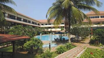 A hotel courtyard with a swimming pool, palm trees, and outdoor seating areas.