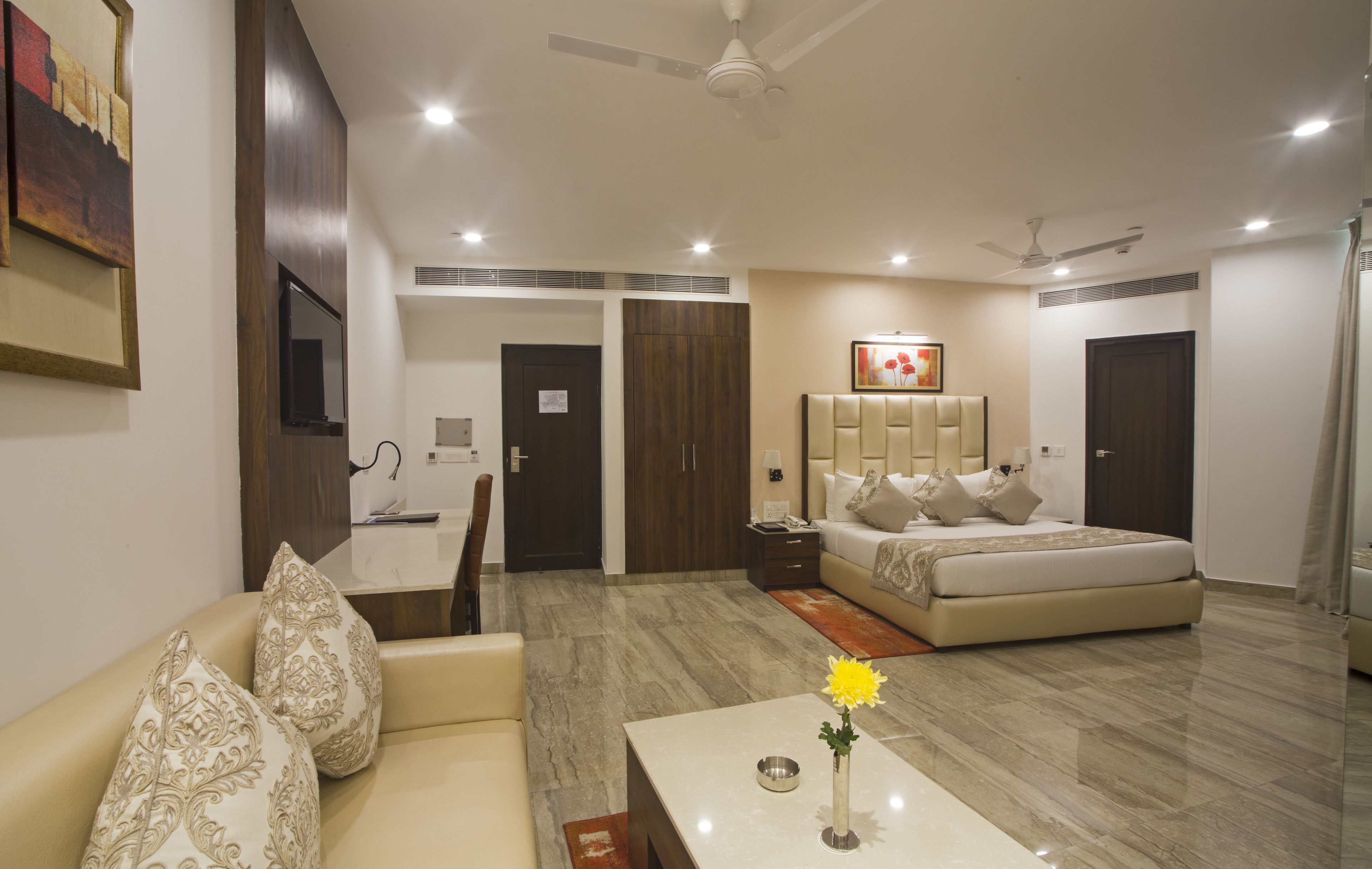 Una habitación de hotel moderna con sofá, cama, zona de comedor y televisión.