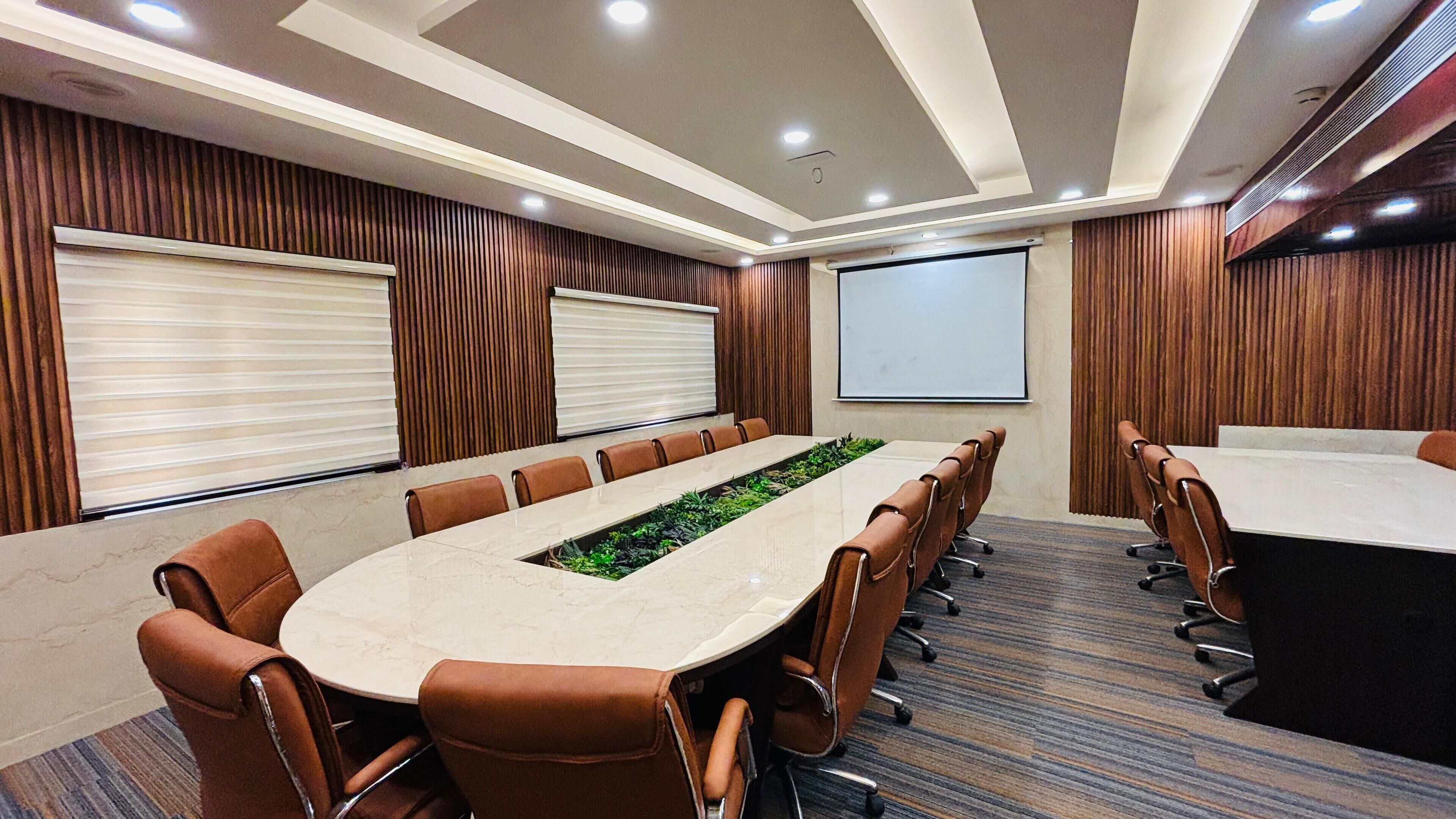A conference room with a long table, brown leather chairs, a projector screen, and wooden paneling on the walls.