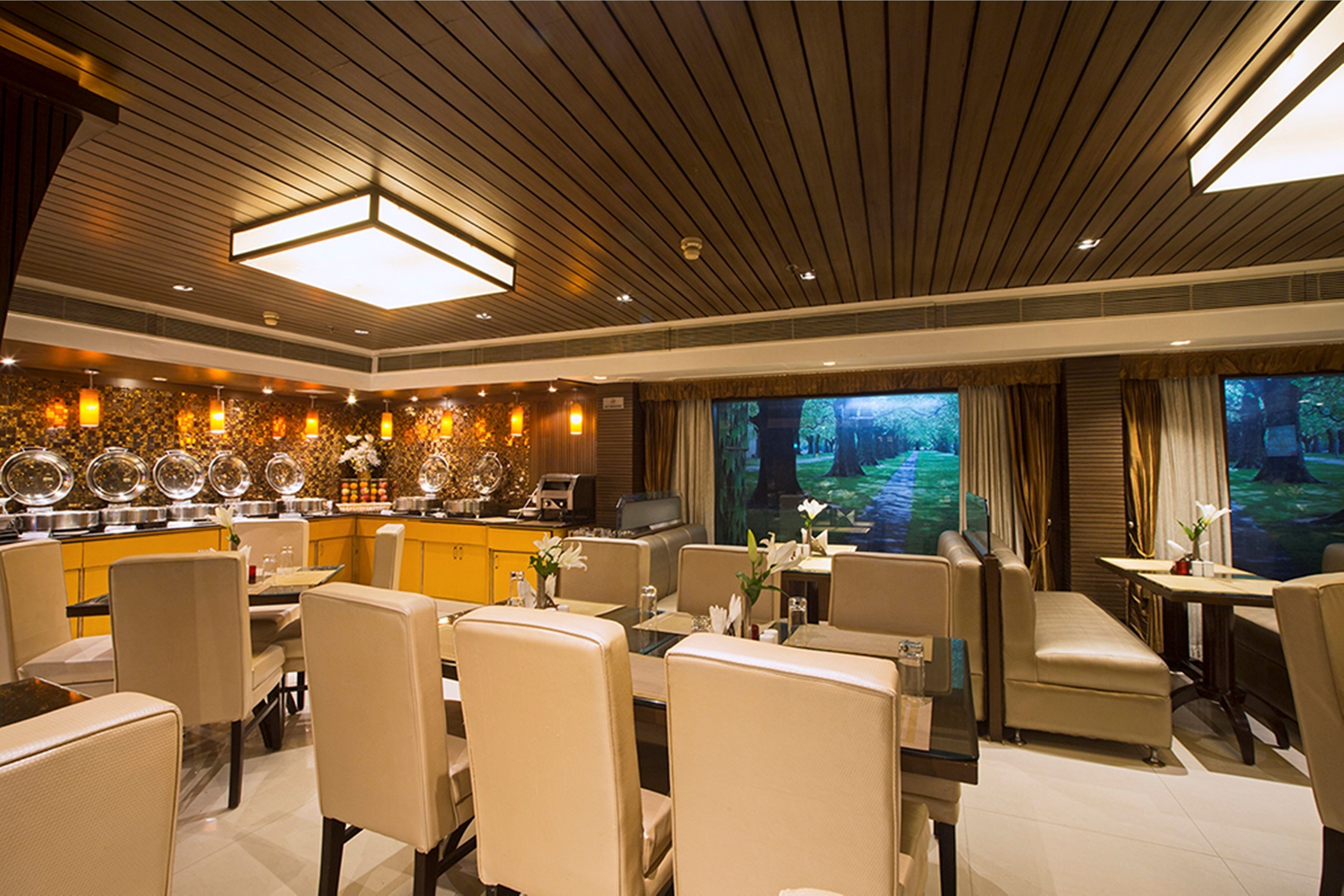 A restaurant with a modern interior, featuring a bar area, multiple dining tables, and comfortable seating.