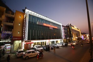 A hotel with a prominent 'Shanti Palace' sign, multiple cars parked in front, and a busy street scene. - Hotel Shanti Palace (New Delhi)