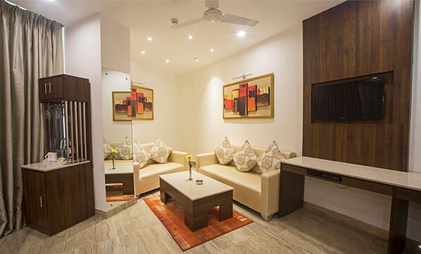 Una sala de estar moderna con un conjunto de sofás, una mesa de centro, un televisor y obras de arte en las paredes.